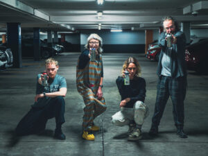 photograph in a dingy car park. four members of pvi collective are posing for the camera with spray cans at the ready